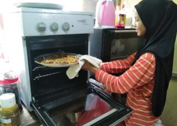 NORAIDA Zulkifli menunjukkan piza yang sudah dimasak di Kampung Tanjung Buluh di Lipis, Pahang. - UTUSAN/HARIS FADILAH AHMAD