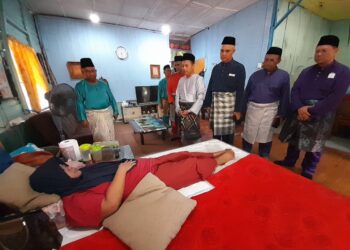 ROHAYU Mohd. Taib (terbaring) menerima kunjungan Aznan Tamin (dua dari kiri) bersama pihak Enproserve (M) Sdn. Bhd. dalam Program Ziarah Kasih di Kampung Bukit Raja semalam.