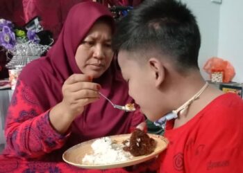 NORIZAN Marsandi menyuap makanan kepada Muhammad Raeez Ramadhan Mohd. Zulkiflee yang menderita penyakit jantung berlubang di Kampung Paya Lang, Batu Anam, Segamat, Johor.