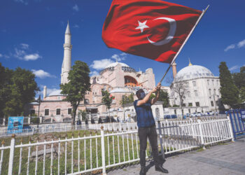 SEORANG lelaki mengibarkan bendera Turki ketika meraikan Hagia Sophia kembali berfungsi sebagai masjid. - AFP