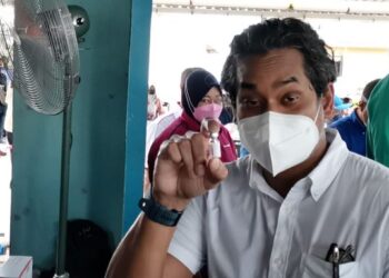 KHAIRY Jamaluddin menunjukkan bebuli vaksin dos tunggal CanSino semasa lawatan di PPV SK Pulau Larapan, Semporna hari ini.