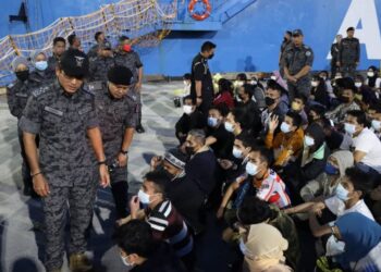 KHAIRUL Dzaimee Daud (depan) memantau proses pengusiran PATI warga Filipina di Pelabuhan Sandakan semalam.-IHSAN IMIGRESEN