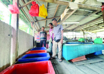 MOHD Shukor Chin (kanan) melihat tong-tong ikan yang kosong berikutan pengurangan hasil diraih oleh nelayan sejak beberapa minggu lalu disebabkan faktor cuaca dan pencerobohan bot nelayan luar di kawasan perairan di Sungai Baru, Perlis. – UTUSAN/ASYRAF MUHAMMAD