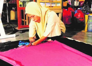 NIK Suriyati Zakaria menyiapkan pakaian yang ditempah pelanggan di rumahnya di Felda Chiku 5, Gua Musang, Kelantan. – UTUSAN/AIMUNI TUAN LAH