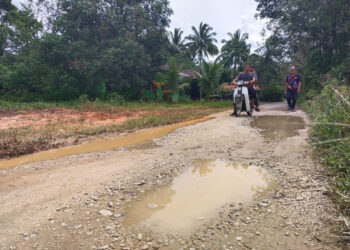 ZAKARIA Mamat (kanan) bersama penduduk menunjukkan laluan yang masih belum berturap di Kampung Sipol, Chetok Pasir Mas, Kelantan. – UTUSAN/YATIMIN ABDULLAH