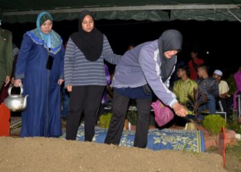 ROHANA Md. Husin (kanan) ibu kepada Allahyarham Abdul Aziz Aznam menyiram  kubur anaknya selepas pengkebumian di Tanjung Rambutan, Ipoh, Perak. - UTUSAN/ZULFACHRI ZULKIFLI