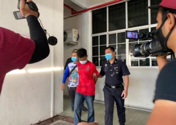 Tertuduh (baju merah) dibawa keluar dari Mahkamah Majistret Kangar, Perlis hari ini, selepas didakwa atas tuduhan memiliki dadah jenis ganja dan methamphetamine pada September lalu.- UTUSAN/NAZLINA NADZARI