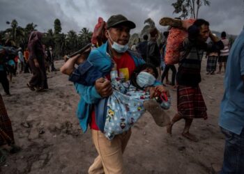 PENDUDUK mendukung seorang kanak-kanak ketika mereka mencari barangan yang masih boleh diambil selepas letusan Semeru di Lumajang, Indonesia. - AFP