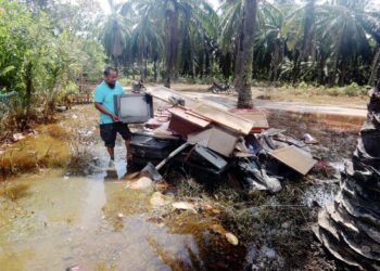 PENDUDUK, Awang Umar, 54, mengasingkan barang yang rosak selepas kejadian banjir di Kampung Lanchang, Merlimau, Jasin, Melaka. – UTUSAN/RASUL AZLI SAMAD