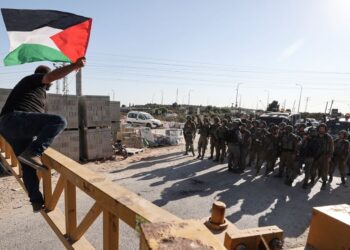 SEORANG penduduk yang membawa bendera Palestin cuba melompat melepasi penghadang dikawal tentera Israel semasa demonstrasi di bandar Salfit, Tebing Barat. - AFP  