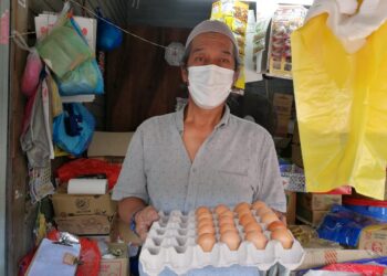 SUHAIMI Ahmad menunjukkan telur gred E yang dijual kedainya selepas terputus bekalan gred A sejak tiga minggu lalu di Pasar Besar Chukai di Kemaman. - UTUSAN/NIK NUR IZZATUL HAZWANI NIK ADNAN