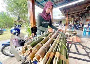 HANAFIZA HASNAN meletakkan pelita buluh di atas motosikal untuk dihantar kepada  pelanggannya di Kampung Kechor, Jalan Kaki Bukit, Kangar, Perlis. -UTUSAN/NAZLINA NADZARI