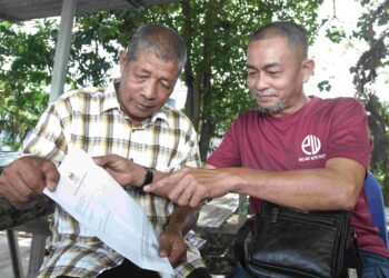 HAMIDAN Yahaya (kiri) menunjukkan keputusan A SPM dalam subjek Matematik kepada rakannya, Badrul Bakar, 54, di Jejawi, Arau, Perlis. – UTUSAN/IZLIZAN OTHMAN