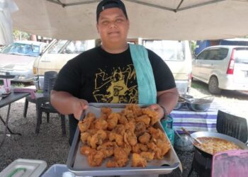 KHAIRUL Anuar Nordin menunjukkan ayam goreng yang dijual pada harga RM1 seketul di Pantai Teluk Lipat, Dungun, Terengganu.- UTUSAN/NIK NUR IZZATUL HAZWANI NIK ADNAN