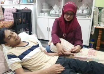 FAIZA Abd. Rashid menemani Muhammad Zarul Haikal Zaidi yang menghidap ketumbuhan dalam paru-paru di Taman Pertang, Kuala Berang, Hulu Terengganu. – FOTO/NOOR HAYATI MAMAT