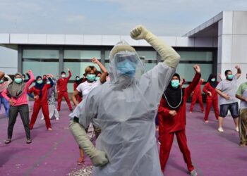 JURULATIH senamrobik memakai peralatan perlindungan diri semasa mengendalikan senaman pagi untuk pesakit Covid-19 di sebuah hotel di Indonesia. -AFP