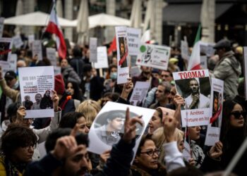 ORANG ramai memegang potret rakyat Iran yang dipenjara dan dihukum mati ketika protes membantah rejim Iran diadakan di Lyon. - AFP   