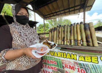 SURIAWATI Yaakub menunjukan pakej lemang dan rendang yang dijual di gerai di Kampung Lepan Jenut, Kuala Krai. - UTUSAN/TOREK SULONG