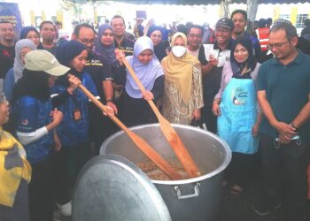 ASMAH Awal (kanan) mengacau bubur lambuk sambil disaksikan mahasiswa dan kakitangan UiTM Cawangan Selangor dekat Puncak Alam di Kuala Selangor, Selangor. 
– UTUSAN/ABDUL RAZAK IDRIS