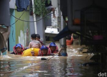 PASUKAN penyelamat membantu dua kanak-kanak mangsa banjir di Kebon Pala, Jakarta Timur.- DETIK.COM