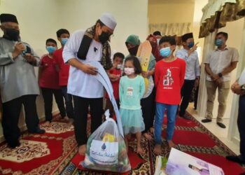 SULAIMAN Md. Ali beramah mesra dengan dua daripada enam beradik yatim piatu selepas majlis penyerahan kunci rumah LPM dengan kos RM40,000 di Kampung Tangga Batu Pekan, Melaka. - UTUSAN/AMRAN MULUP