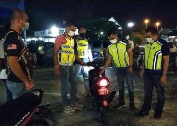 ROSLAN Mohamed (kanan) memeriksa motosikal yang ditahan dalam Operasi Bersepadu Samseng Jalanan di Ipoh malam tadi. - UTUSAN