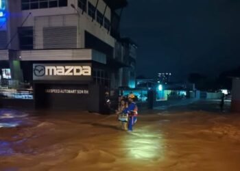 ANGGOTA APM melakukan pemindahan mangsa banjir di sekitar Penampang semalam.-IHSAN APM