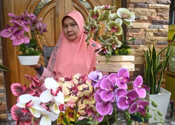 TENGKU Aspaniza Tengku Aziz menunjukkan pelbagai gubahan bunga orkid plastik ditempah pelanggan.
– UTUSAN/PUQTRA HAIRRY