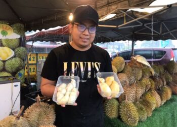 AMIEL Shafiq Izril Azman menunjukkan durian yang dijual pada harga Menu Rahmah di gerainya di Simpang Pulai, Ipoh, Perak. - MINGGUAN/LIYANA RAMLI