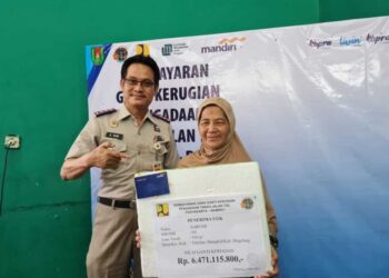 SARUMI menerima replika cek duit selepas tanahnya diambil kerajaan untuk pembangunan tol Yogyakarta-Bawen. - AGENSI