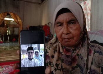 SEMEK Abdul Rahman menunjukkan gambar anak dan menantunya yang maut dalam kemalangan jalan raya di Kilometer 76, Jalan Raya Timur Barat (JRTB) Gerik-Jeli di Perak. - UTUSAN/NOOR HAYATI MAMAT