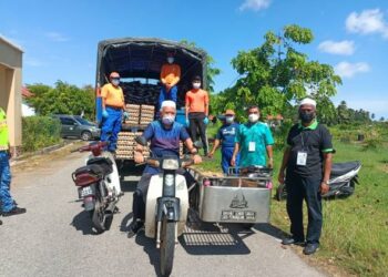 MOHD. Adanan Hassan menunggang motosikal roda tiga ketika penyerahan bakul makanan kepada penduduk di PKPD Taman Sri Bayu, Tumpat, hari ini. - UTUSAN/ROHANA MOHD. NAWI