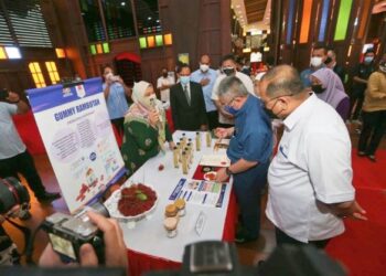 DR. ADHAM (berbaju biru) mendengar penerangan petugas ketika melawat tapak pameran di UMK Kampus Kota di Pengkalan Chepa, Kota Bharu hari ini. - UTUSAN/ROHANA MOHD. NAWI