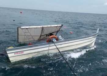 BOT pemancing yang terbalik selepas terlanggar rantai sauh kapal dagang ditunda ke Jeti Pulau Pangkor petang semalam. - UTUSAN/IHSAN MARITIM MALAYSIA PERAK