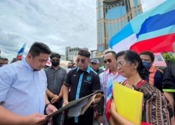 HOLLYNAH Mopuas (kanan) berkongsi masalah mereka kepada Fairuz Renddan (kiri), turut kelihatan Hishamuddin Hashim di hadapan Menara Kinabalu hari ini.