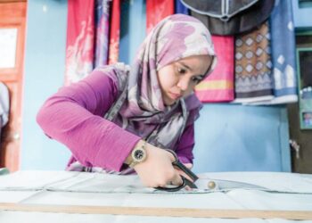 UMI UMAIRAH Lokman menyiapkan tempahan baju raya pelanggan di kedainya di Ayer Molek, Melaka. - UTUSAN/SYAFEEQ AHMAD
