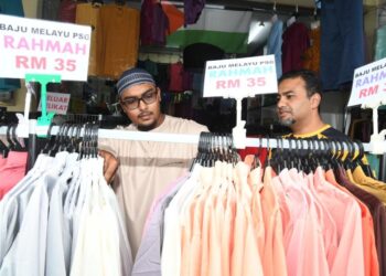 FAIZ Ismail (kanan) melayan pelanggan yang memilih baju Melayu yang ditawarkan pada harga Rahmah serendah RM35 di Toko Ar-Rayyan di Kompleks Tok Arau, Perlis. - UTUSAN/IZLIZAN OTHMAN