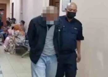 TERTUDUH John Kennedy Sanggah (kiri) diiring keluar di Mahkamah Majistret Tawau semalam