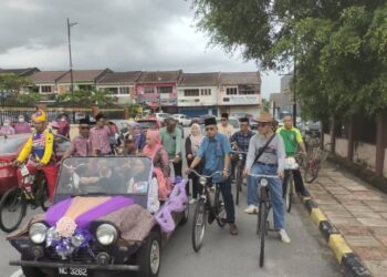 PASANGAN pengantin yang menaiki kereta klasik jenis Mini Moka diiringi kayuhan 22 buah basikal tua sejauh 500 meter ke Dewan Sri Rembau, Rembau. – UTUSAN/NOR AINNA HAMZAH