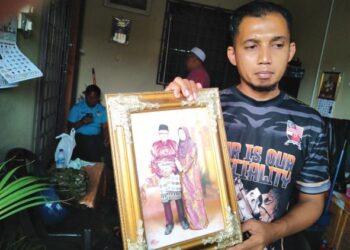 MUHAMMAD TARFIZAM Talib menunjukkan potret ibu dan bapanya yang maut dalam kemalangan jalan raya di Taman Muhibbah, Jerantut, Pahang. - UTUSAN/HARIS FADILAH AHMAD