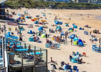 ORANG ramai mengambil kesempatan bersantai sambil menikmati cuaca panas di pantai Newquay di Cornwall. - SWNS