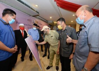 HAJIJI Noor (tiga kanan) menandatangani plak pelancaran pemasangan 50 VSAT CONNECTme Now di Kudat hari ini.-Ihsan Jabatan Ketua Menteri