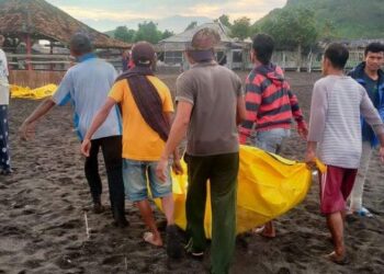 PENDUDUK membantu pihak berkuasa mengangkat satu daripada mayat mangsa yang dihanyutkan ombak di Pantai Payangan di Jamber, Jawa Timur. - AGENSI