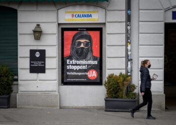 ENDUDUK berjalan melepasi sebuah poster kempen larangan burqa di jalanan Zurich, Switzerland. - AFP