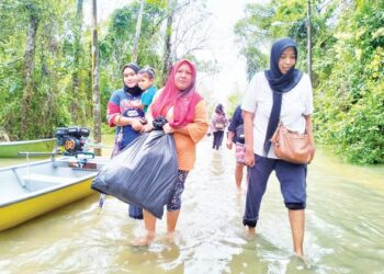 JAMILAH Mohamad (kanan) membawa barang berpindah ke PPS kerana trauma dengan banjir berulang tiga kali di Kampung Serongga, Repek Pasir Mas, Kelantan. - UTUSAN/ROHANA ISMAIL