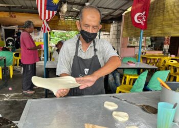 WAN Hassan Wan Omar menyediakan roti canai untuk pelanggan di kedainya di Bandar Baru, Gua Musang, Kelantan. – MINGGUAN/AIMUNI TUAN LAH