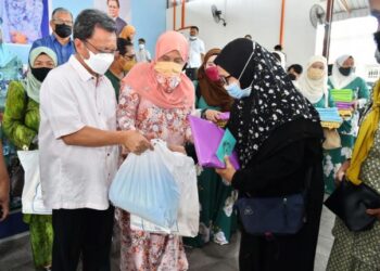 MOHD. Shafie Apdal (kiri) bersama isteri, Shuryani Shuaib (dua kiri) menyampaikan sumbangan kepada salah seorang penerima di Semporna hari ini.