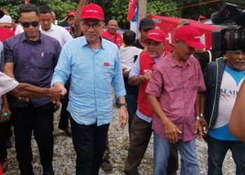 ANWAR Ibrahim disambut penyokong pada program sembang santai Parlimen Pasir Salak hari ini. - UTUSAN/AIN SAFRE BIDIN