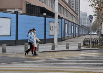 PENDUDUK berjalan di sebelah Pasar Makanan Laut Huanan yang ditutup, di Wuhan, wilayah Hubei, tengah China. - AFP