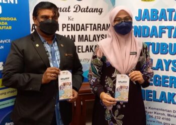 VP Shanmugam (kiri) dan Nurhafidah Ali menunjukkan risalah MyIce di Pejabat ROS Melaka, Ayer Keroh, Melaka. - UTUSAN/AMRAN MULUP
